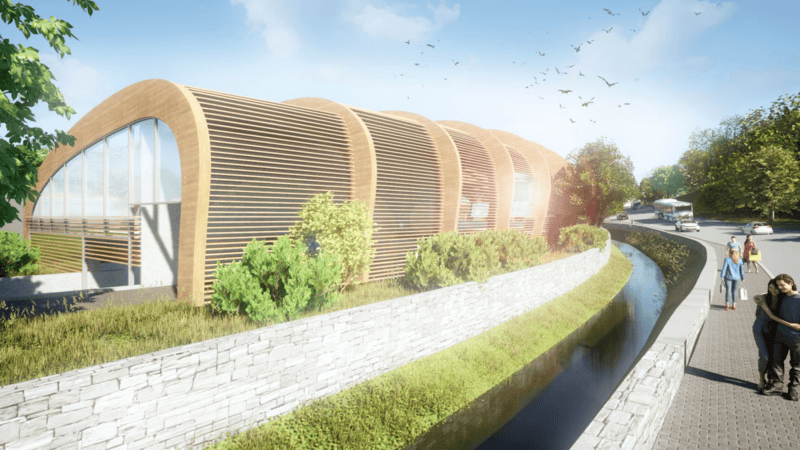 Nahansicht der modernen Holzlamellen-Fassade eines Gebäudes an einem kleinen Kanal; im Vordergrund ein gepflasterter Gehweg mit Passanten.